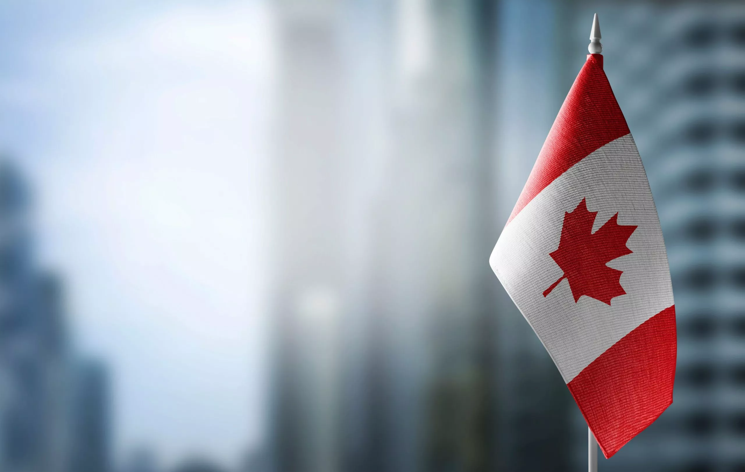Canadian flag with skyscraper buildings in the background to symbolize
